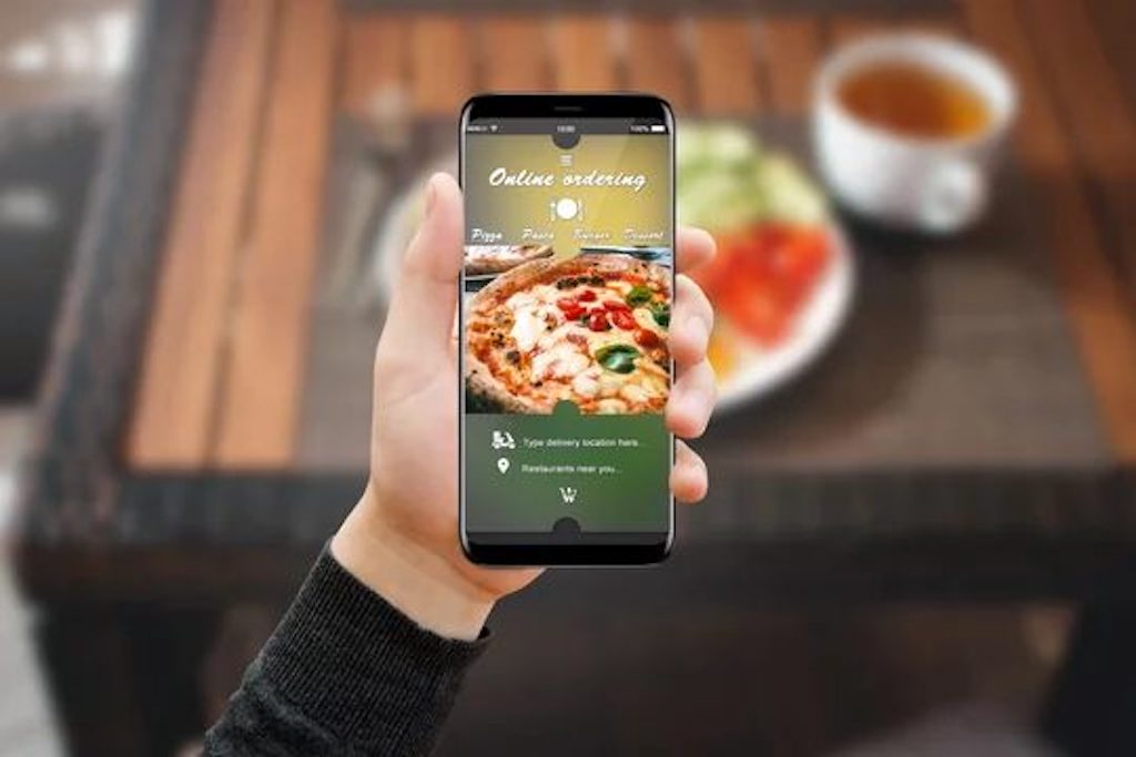 A hand holds a phone with the GrabFood Thailand app open