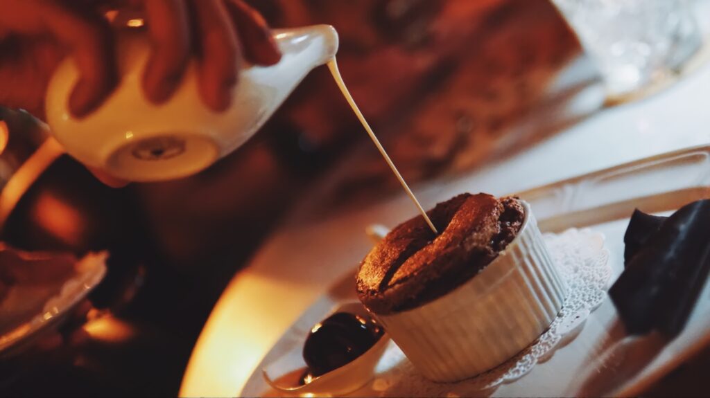 Hot cream is poured over a fresh chocolate souffle