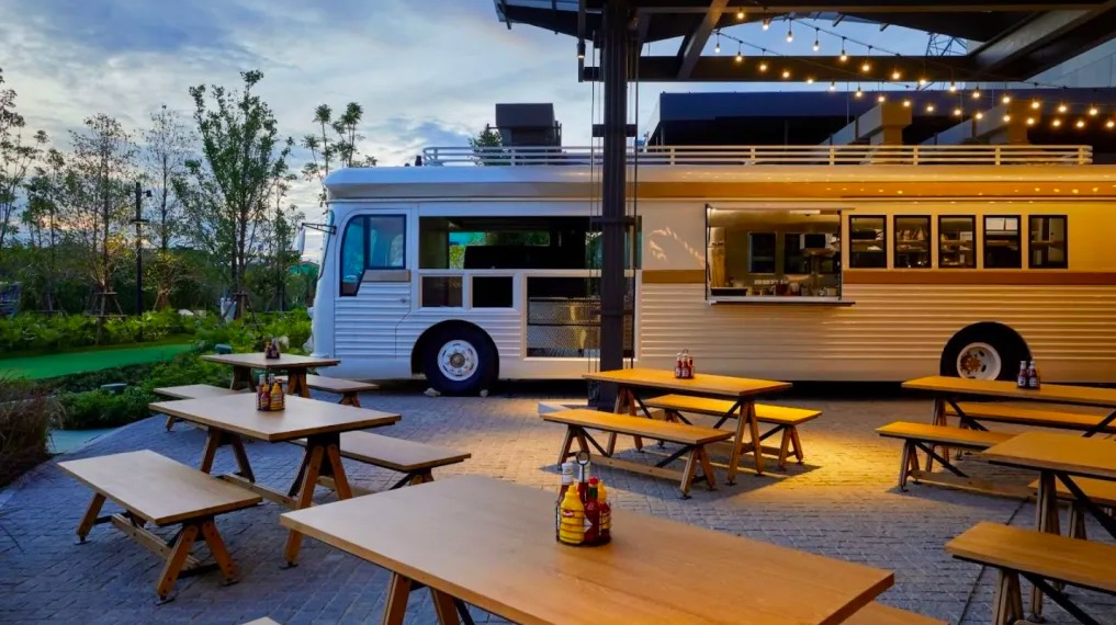 A food bus with picnic tables in the foreground