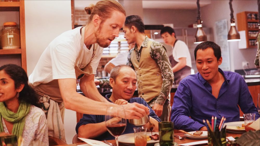 A chef serves a table of dinner guests at Localab