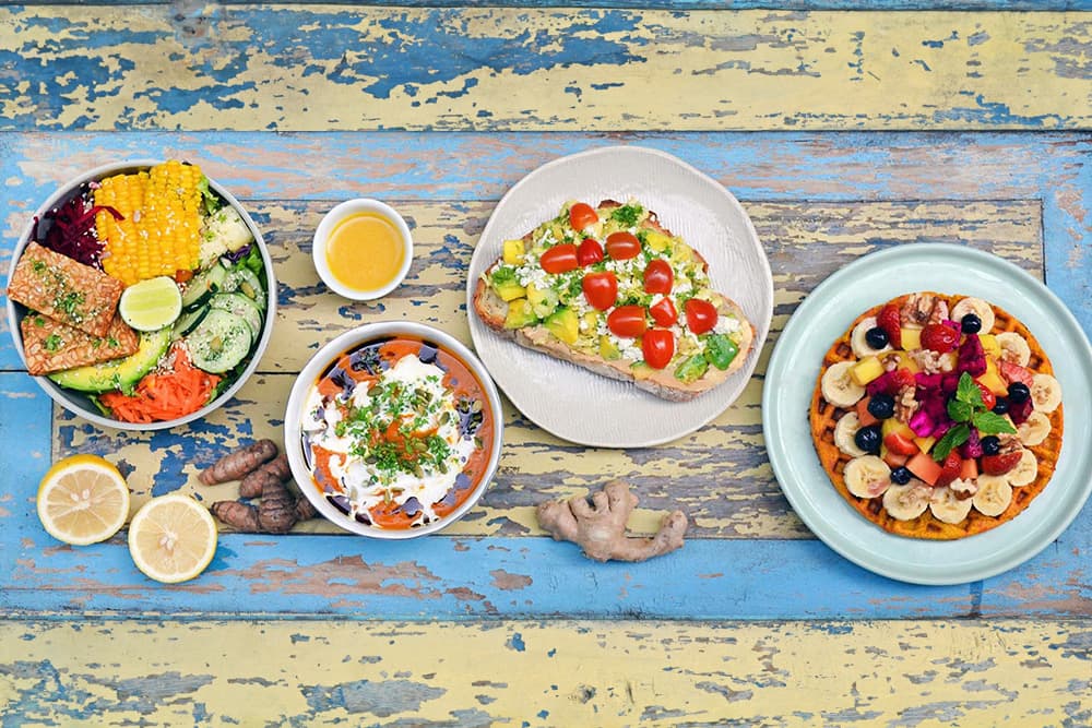 A spread of plates with healthy food on a colorful wooden table